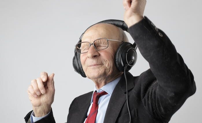 Zdjęcie dekoracyjne. Starszy mężczyzna słucha muzyki na słuchawkach