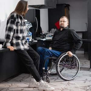 A friendly interaction between a barista and a wheelchair user in a modern cafe setting.